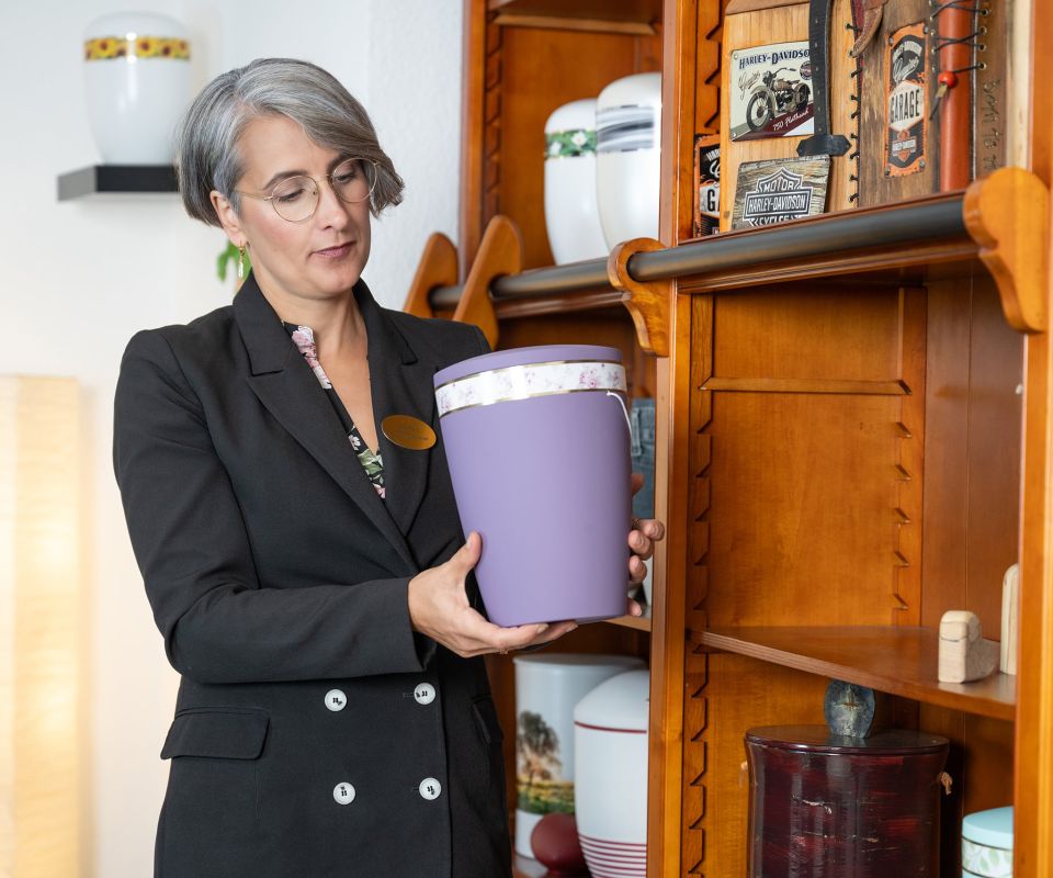 Janet Tarin trägt eine lila farbene Urne